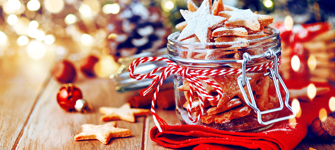 An airtight jar containing Christmas cookies in a festive setting.
