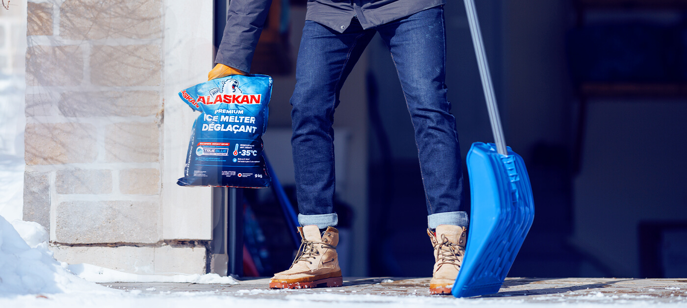 A man uses Alaskan de-icer to melt ice and make it easier to clear snow from his driveway and path.