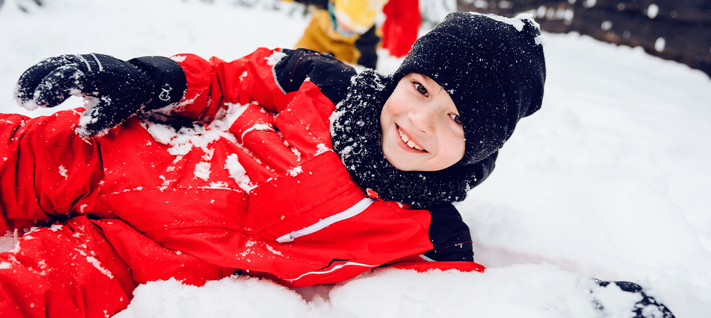 A smiling boy is having fun building a fort in the snow.