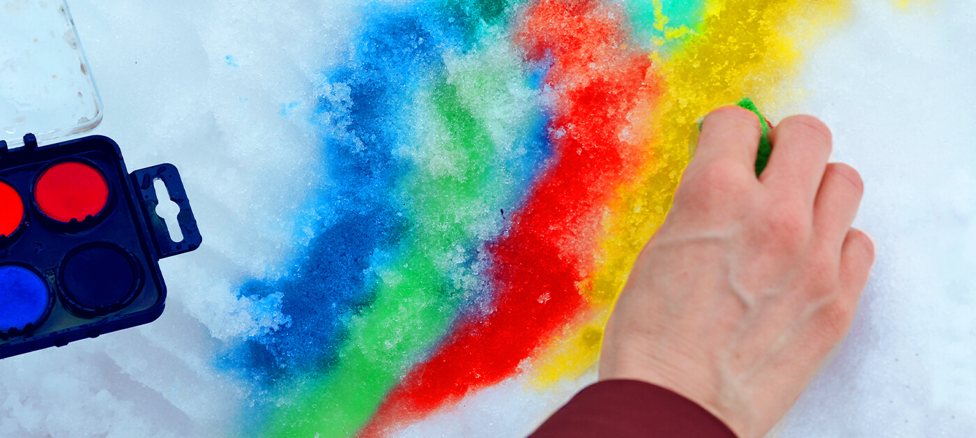 A person is painting on the snow with washable gouache tablets.