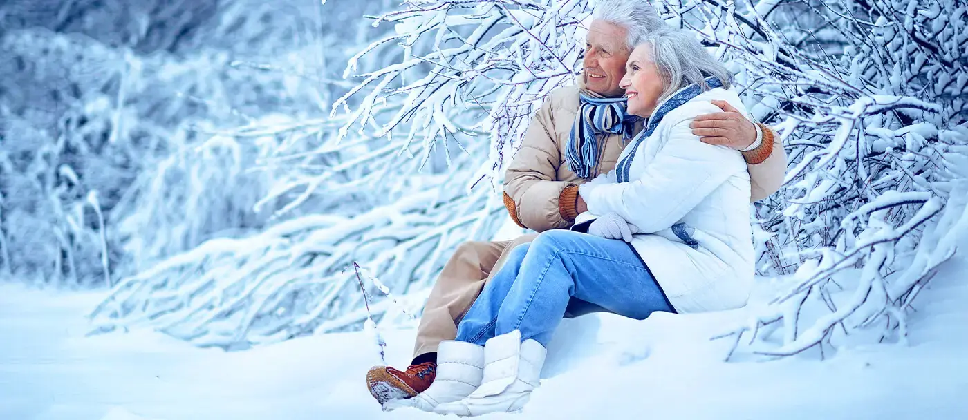 A retired couple enjoy the winter season in a snowy landscape.